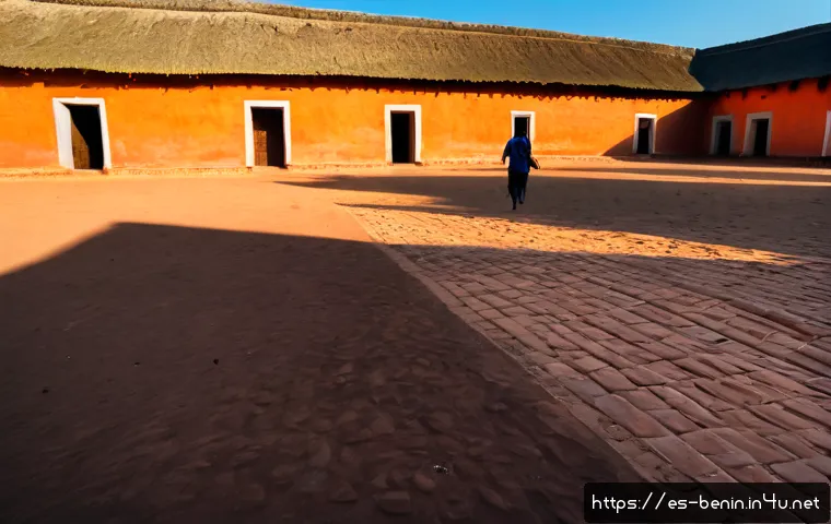 베냉의 유네스코 문화유산 - Photorealistic wide-angle view of the Royal Palaces of Abomey in Benin, sunlit red-earth courtyard f...